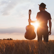 Man met gitaar tijdens zonsondergang