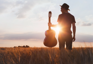 Man met gitaar tijdens zonsondergang